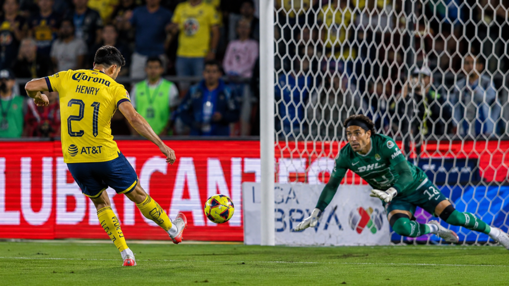 Delantero se lamenta tras fallar un penal frente al portero rival en un partido nocturno.